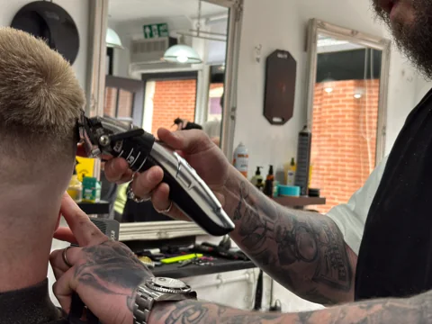 A barber carefully blending the sides of a client’s haircut